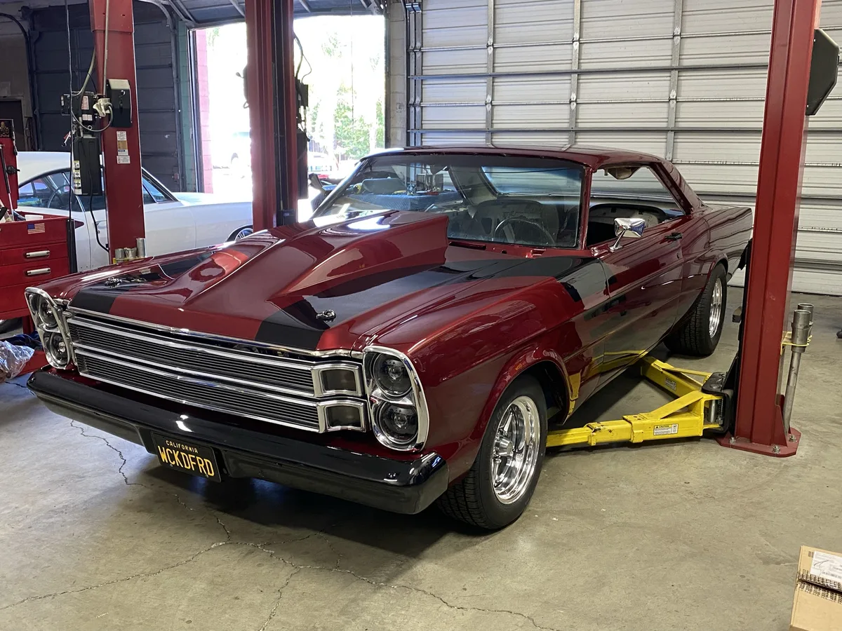 Red and maroon classic convertible on lift during restoration